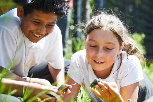 Two children measuring temperature outside with micro:bits