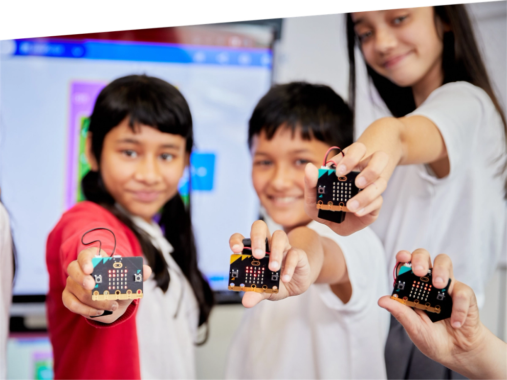 children in class smiling and holding micro:bits